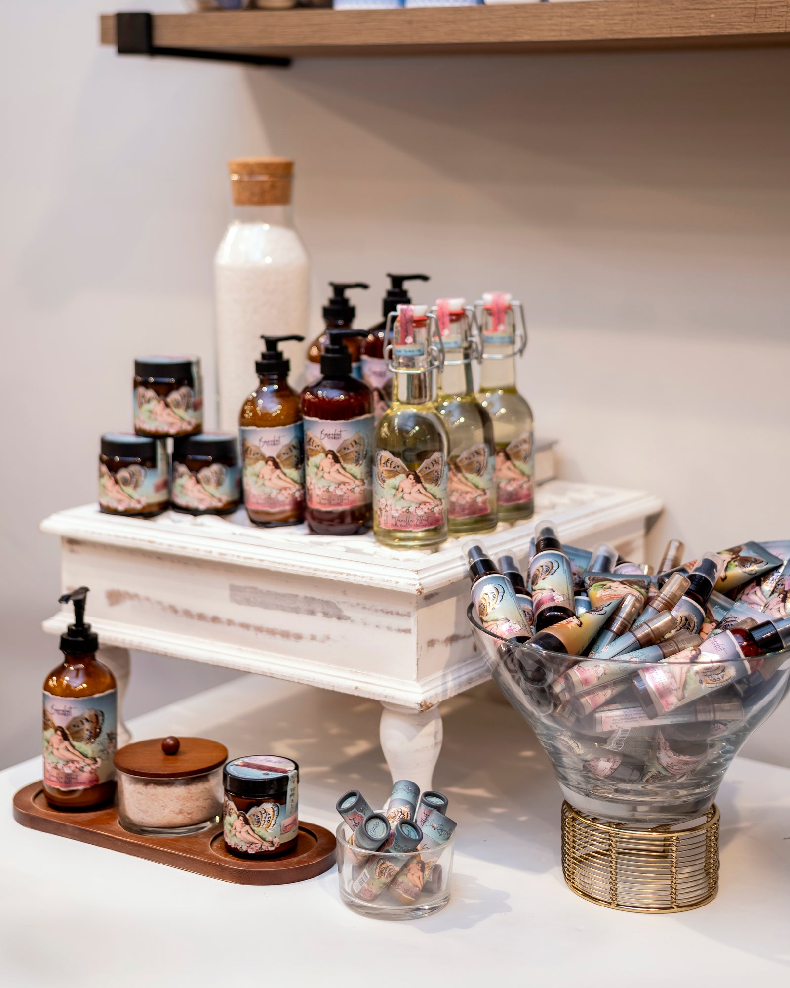 A pump bottle of The Vanilla Effect body cream with a label featuring a fairy illustration and text indicating the product name and scent.